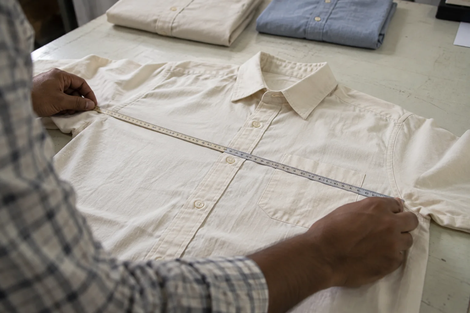 chest-width measurement of a cotton shirt at a factory inspection table