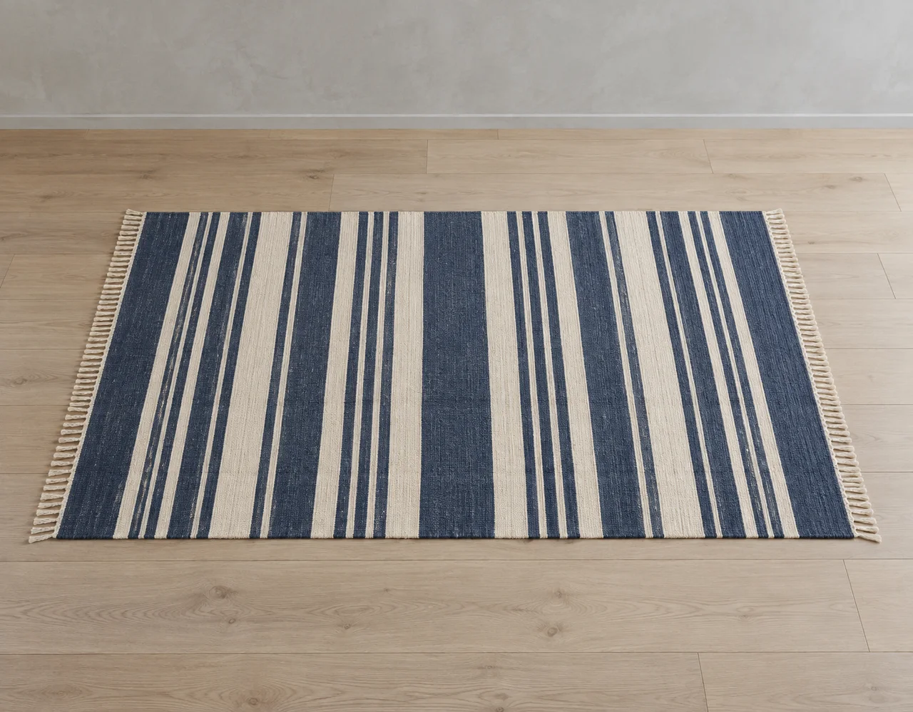 Indigo and ivory striped cotton dhurrie with both fringed ends visible on an oak floor