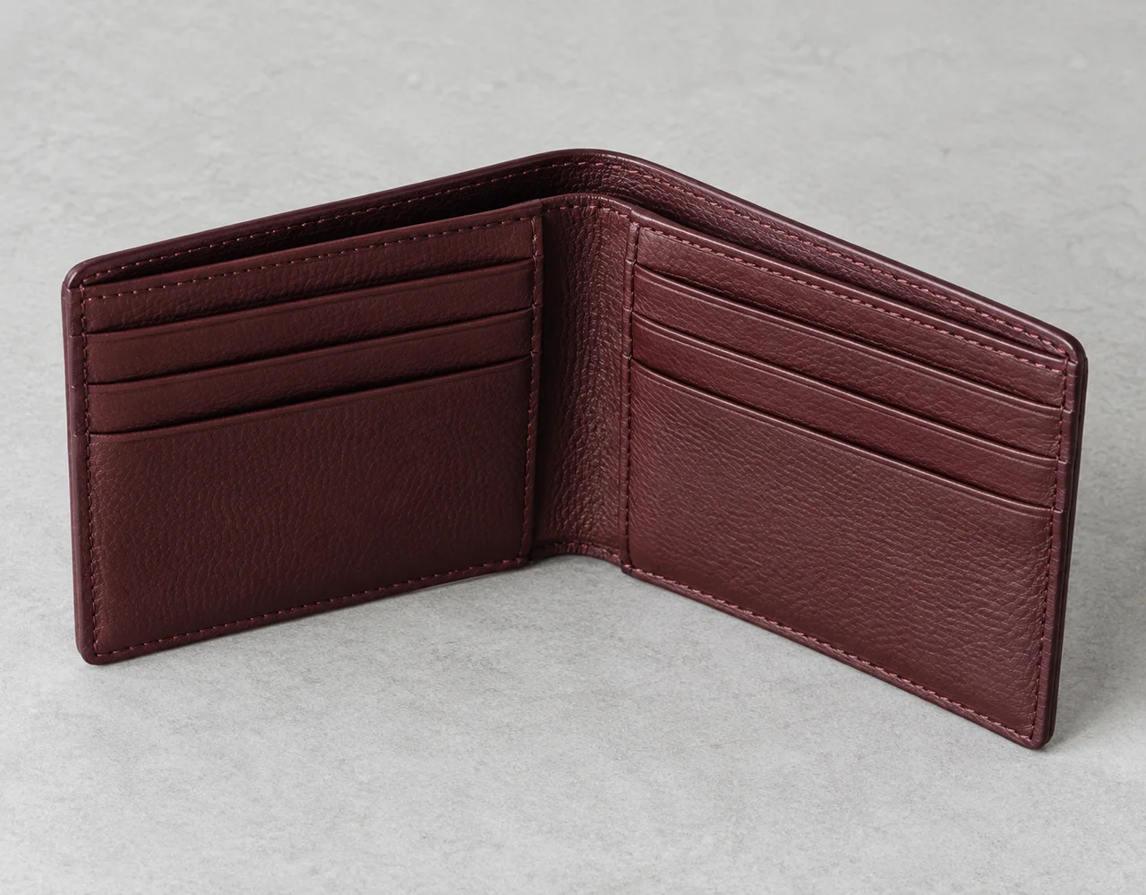 Open burgundy leather bifold wallet showing card pockets and stitched edges