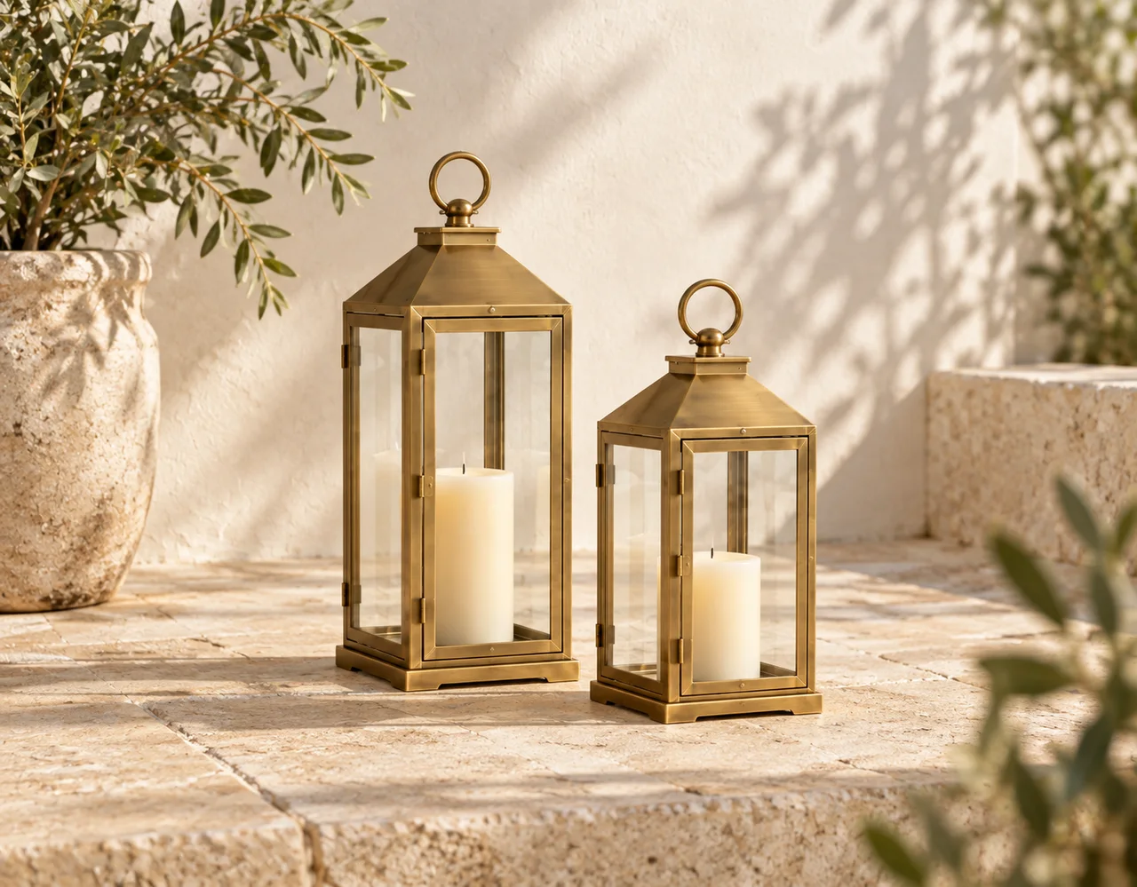 Two decorative metal-and-glass lanterns with unlit candles on a patio
