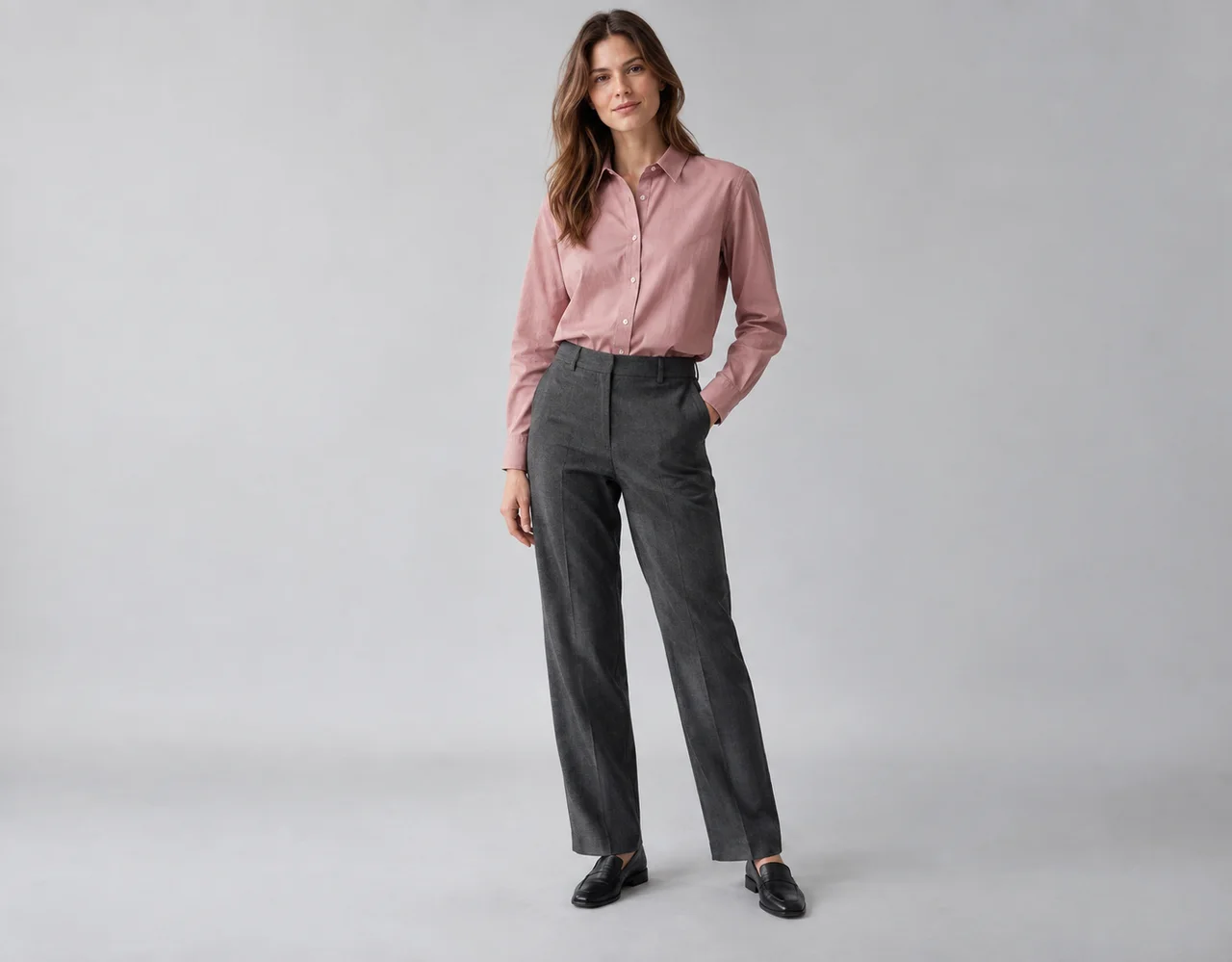Adult model wearing a dusty-rose button-front blouse and charcoal trousers